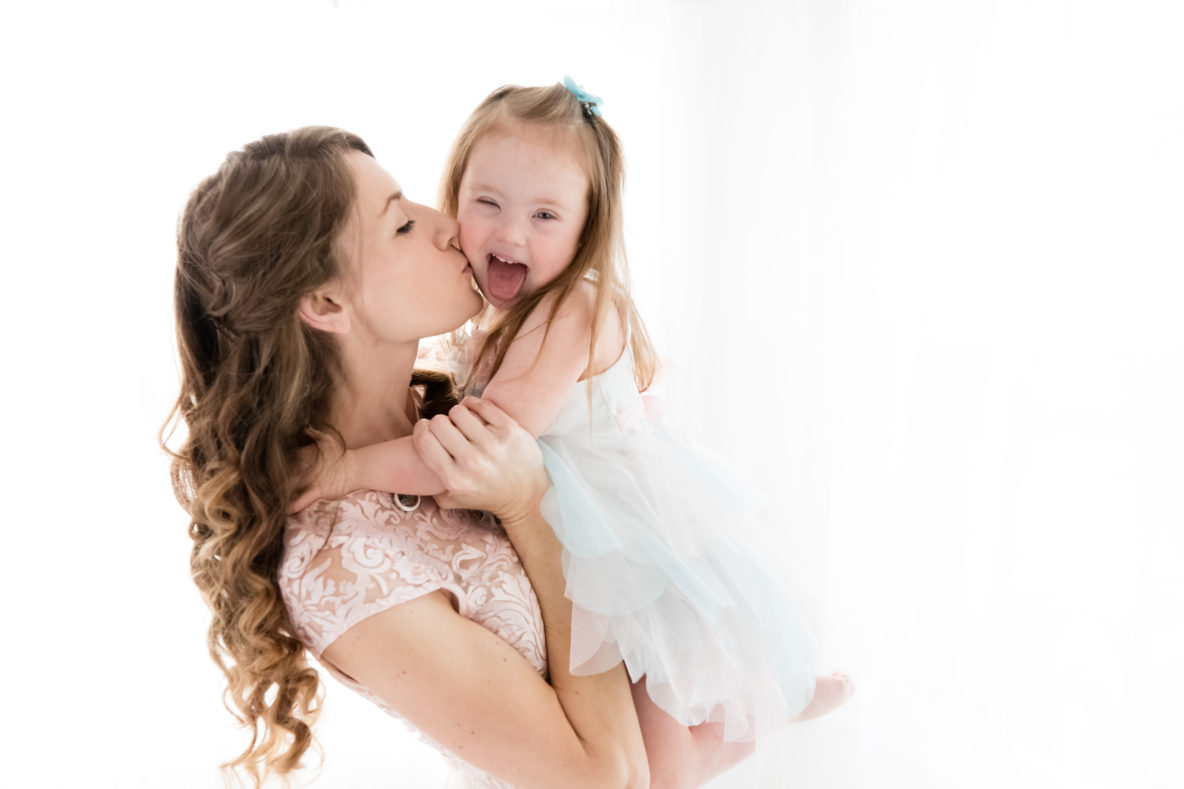 mom kissing daughter with down syndrome